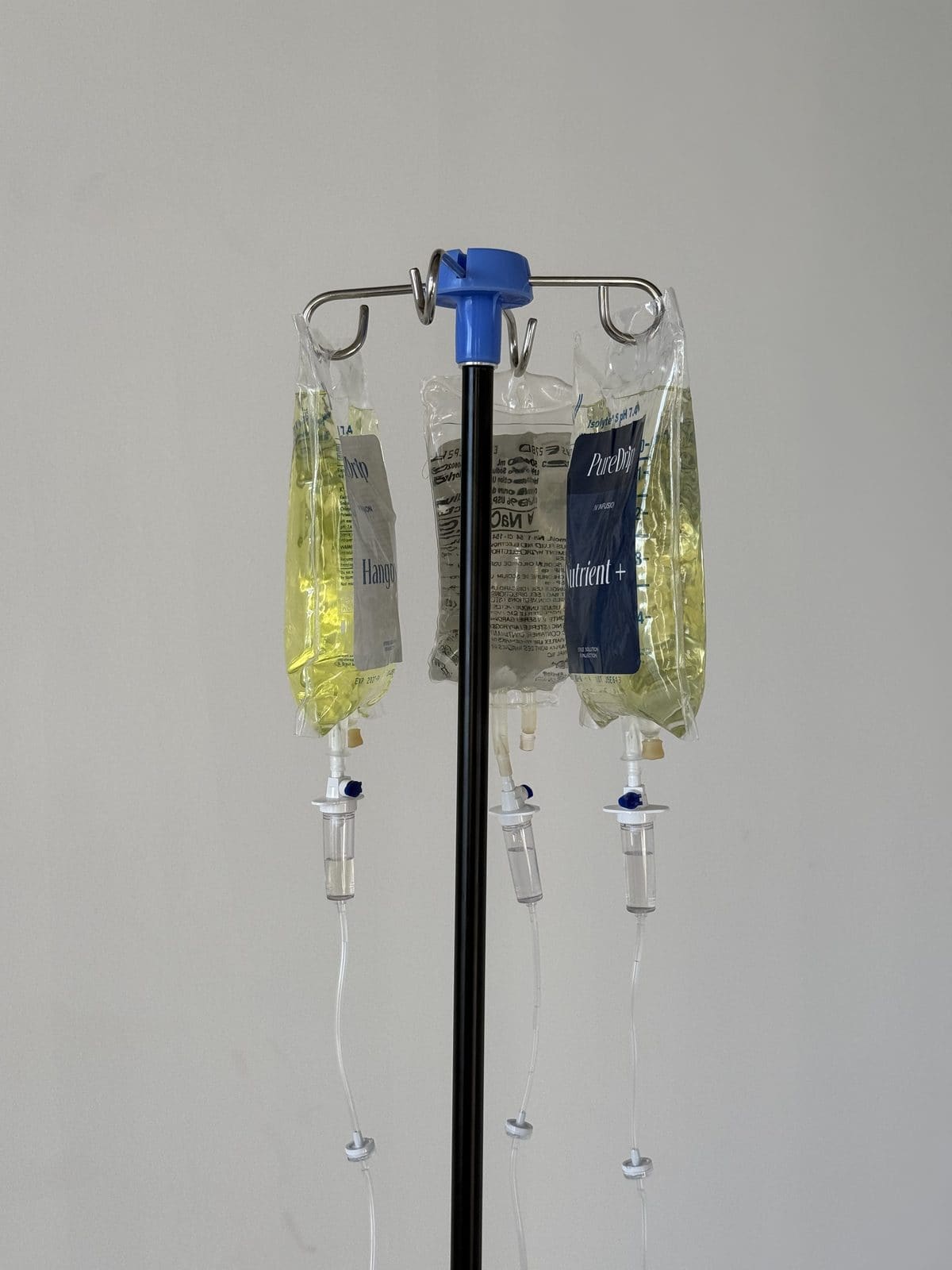 Branded Pure Drip IV infusion bags on an IV stand